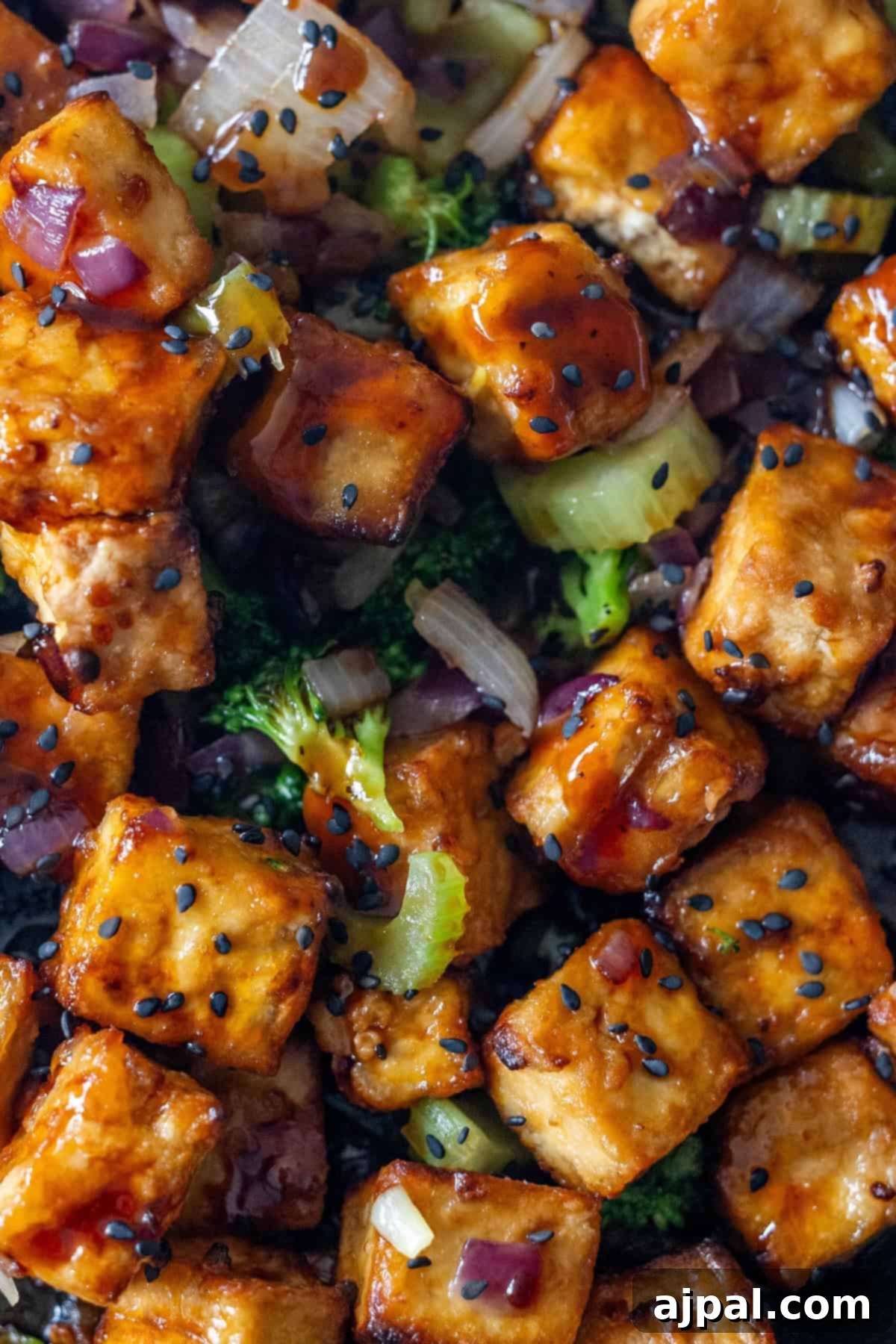 Sizzling Tofu Stir-Fry 4 Close-up of Tofu Stir Fry with tofu cubes, broccoli, onions, celery, and sesame seeds in a glossy sauce.
