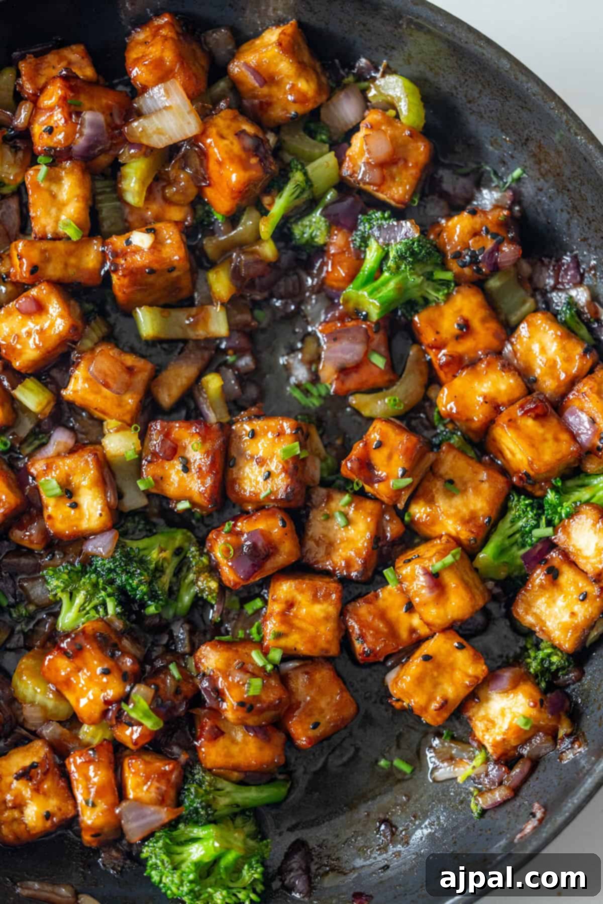 Sizzling Tofu Stir-Fry 5 Pan of Crispy Tofu stir-fried with broccoli, onions, and savory sauce in a skillet.