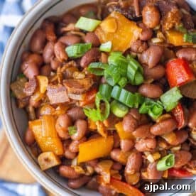 Authentic Mexican Charro Beans Recipe with Bacon and Chiles 14 A bowl of delicious Mexican beans mixed with diced bell peppers, onions, and topped with chopped green onions.