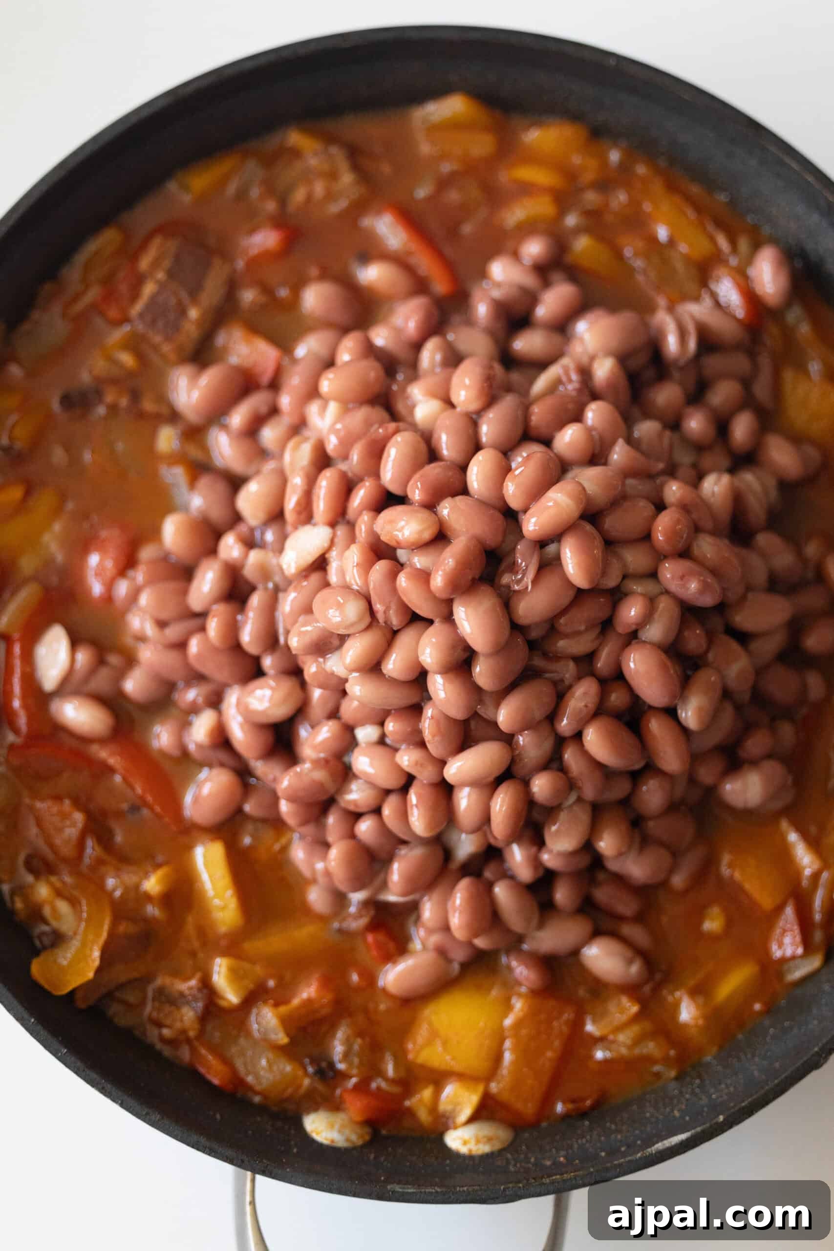 Authentic Mexican Charro Beans Recipe with Bacon and Chiles 8 A bowl of cowboy beans mixed with chopped bell peppers and onions.