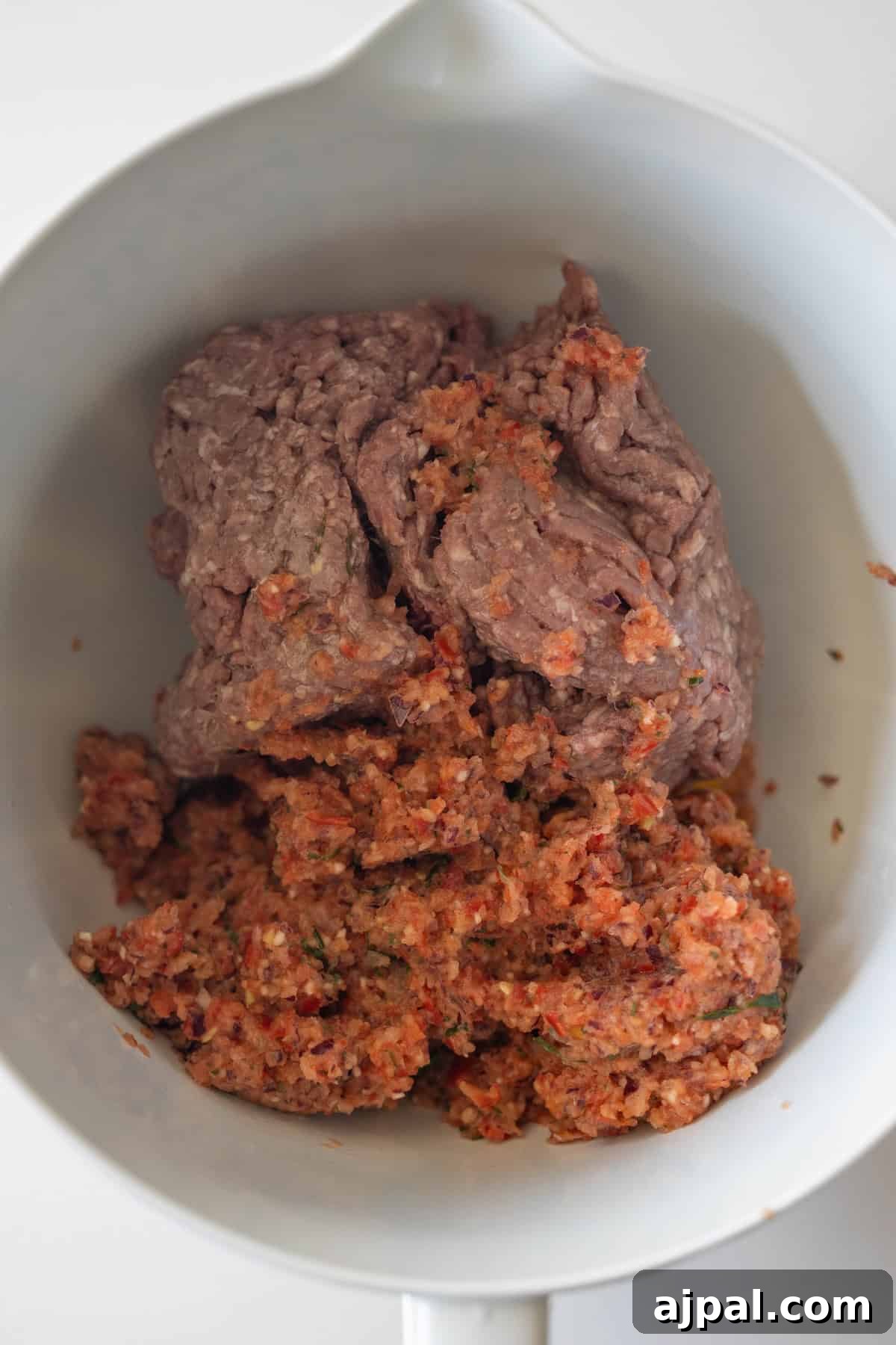 Armenian Spiced Lamb Kebabs Recipe with Authentic Seasoning 7 Ground beef and a mixture of finely chopped vegetables or seasonings come together in a white mixing bowl, perfect for preparing flavorful Armenian spiced meat kebabs.