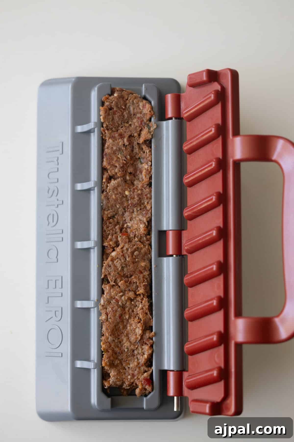 Armenian Spiced Lamb Kebabs Recipe with Authentic Seasoning 9 A close-up of spiced meat mixture packed inside a gray and red plastic mold labeled "Trustella ELROI" on a light surface, perfect for making Armenian kebabs.