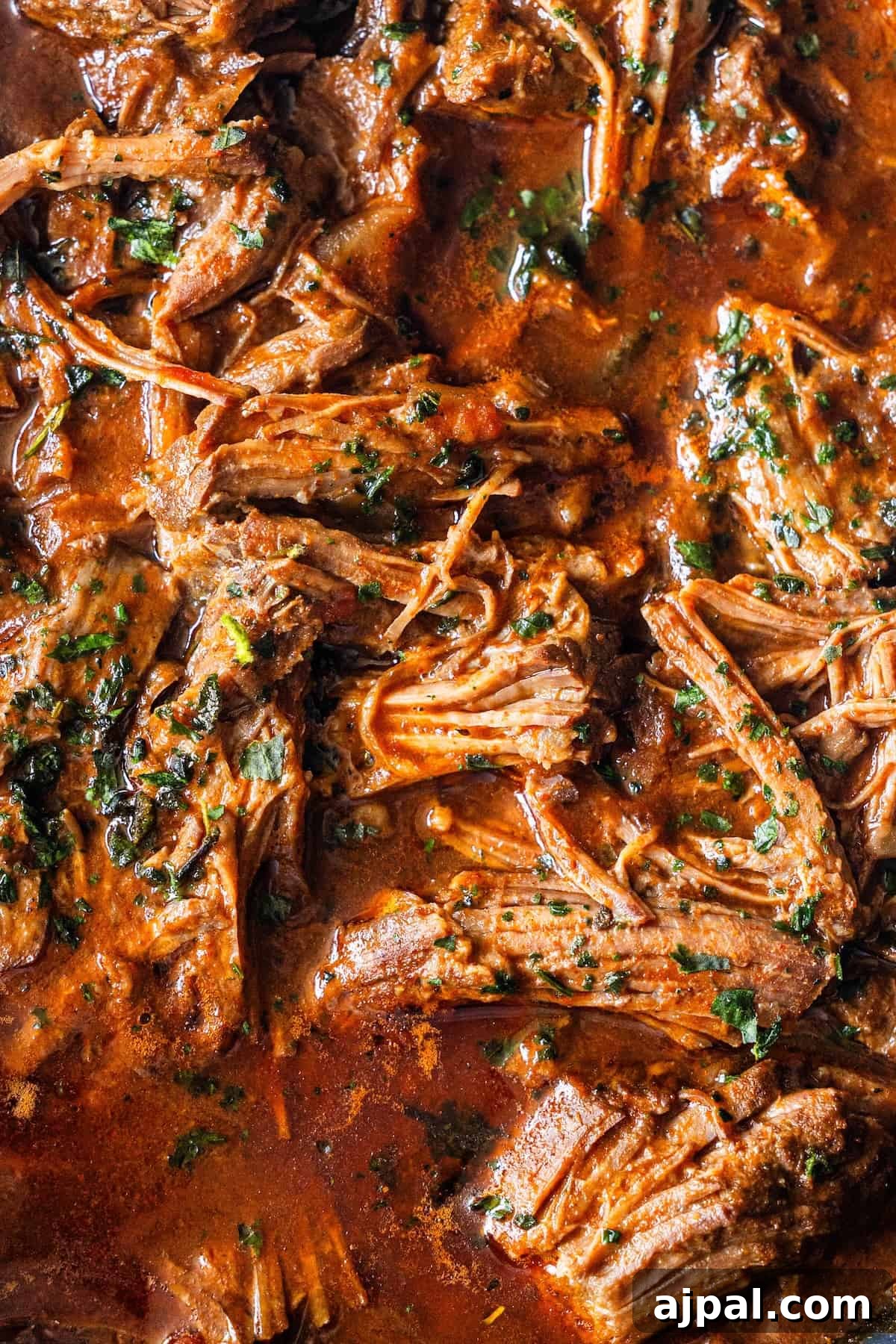 Authentic Birria Tacos Recipe: Juicy Mexican Beef Tacos 9 Close-up of shredded beef in a rich, red sauce.