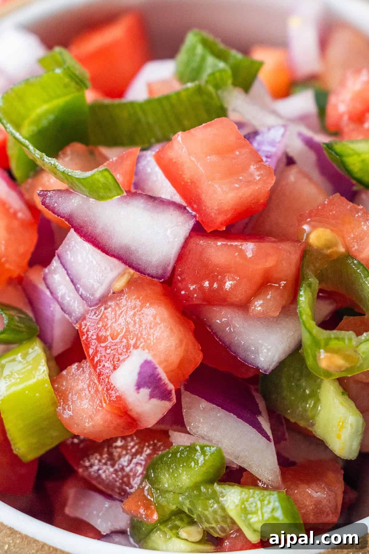Pico de Gallo Recipe: Fresh Mexican Tomato Salsa 4 Close-up of a salad with diced watermelon, red onion, and green pepper slices in a white bowl.