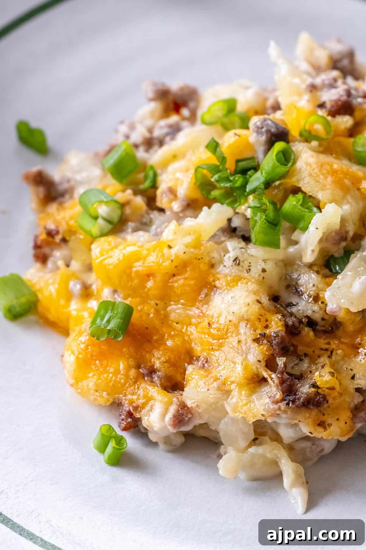 30 Back-to-School Meals That Reheat Perfectly 9 A serving of cheesy casserole with ground beef, topped with chopped green onions, on a white plate.