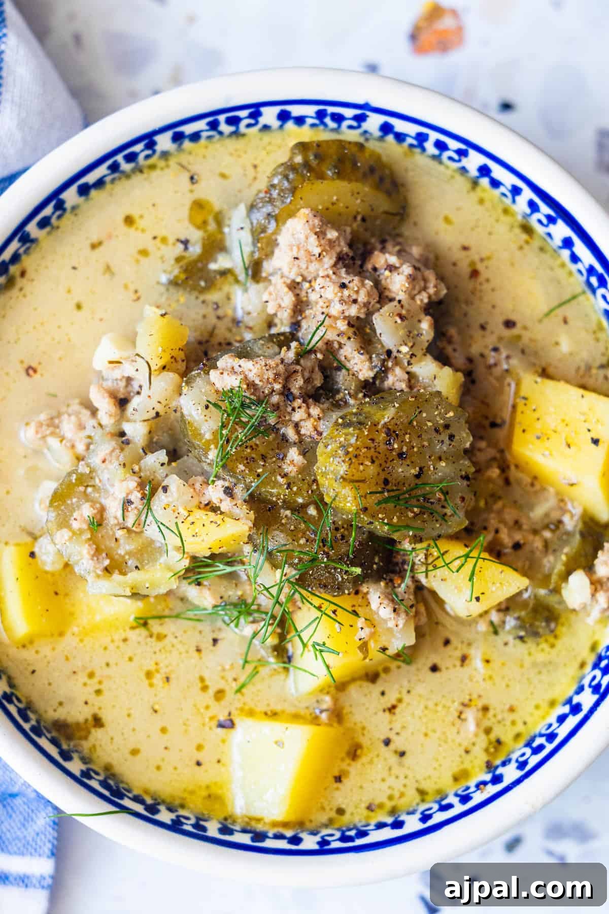 A bowl of creamy sausage soup with diced potatoes, celery, herbs, and pepper.